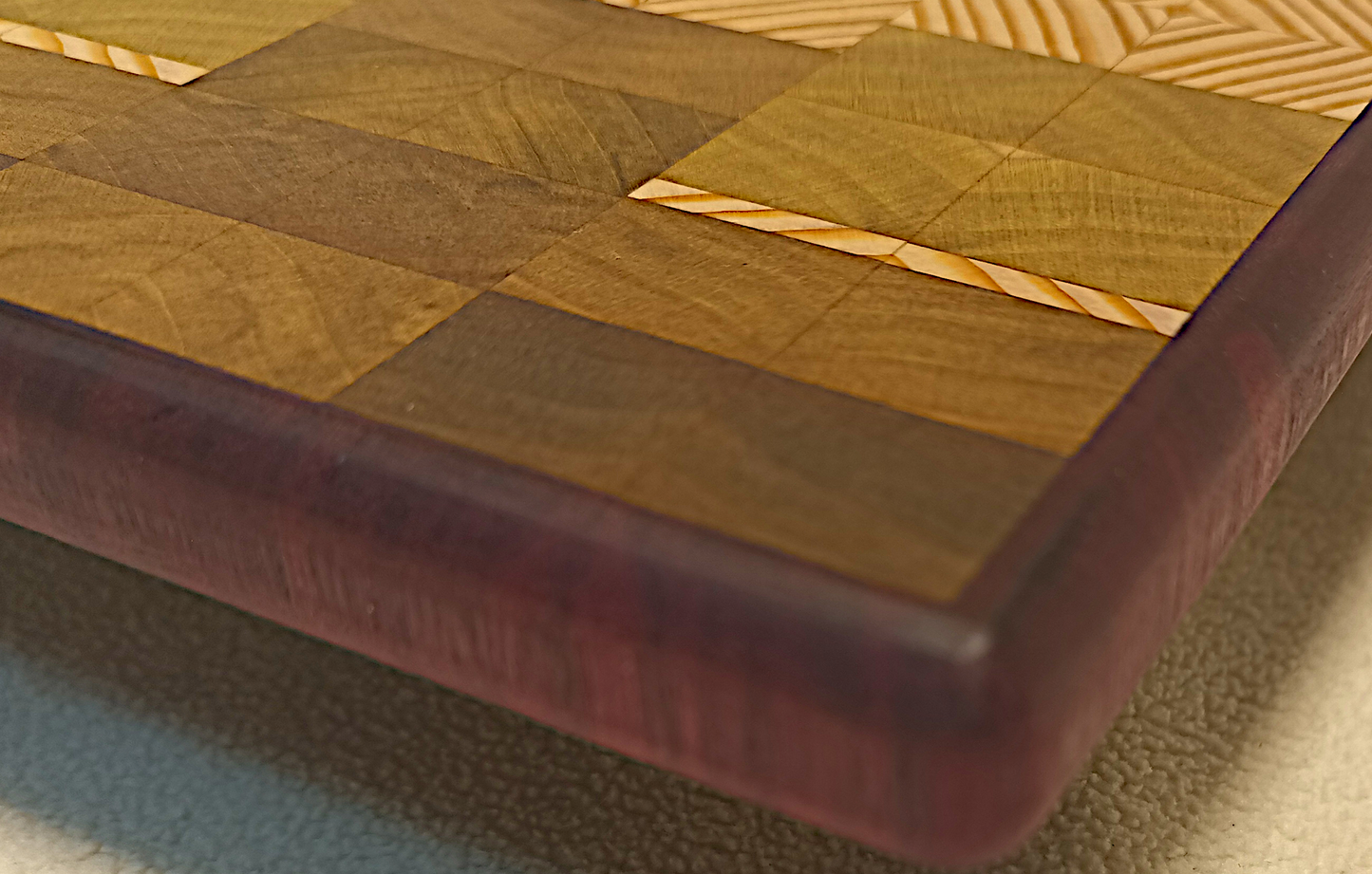 vtw versatile trees woodwork corner view of a thin, large size end grain cutting board made with purple heart walnut, Hemlock, and Poplar. Perfect for a home or professional chef, this board provides a usable work area without raising the work surface very far above the counter top and softer woods are easier on expensive knives