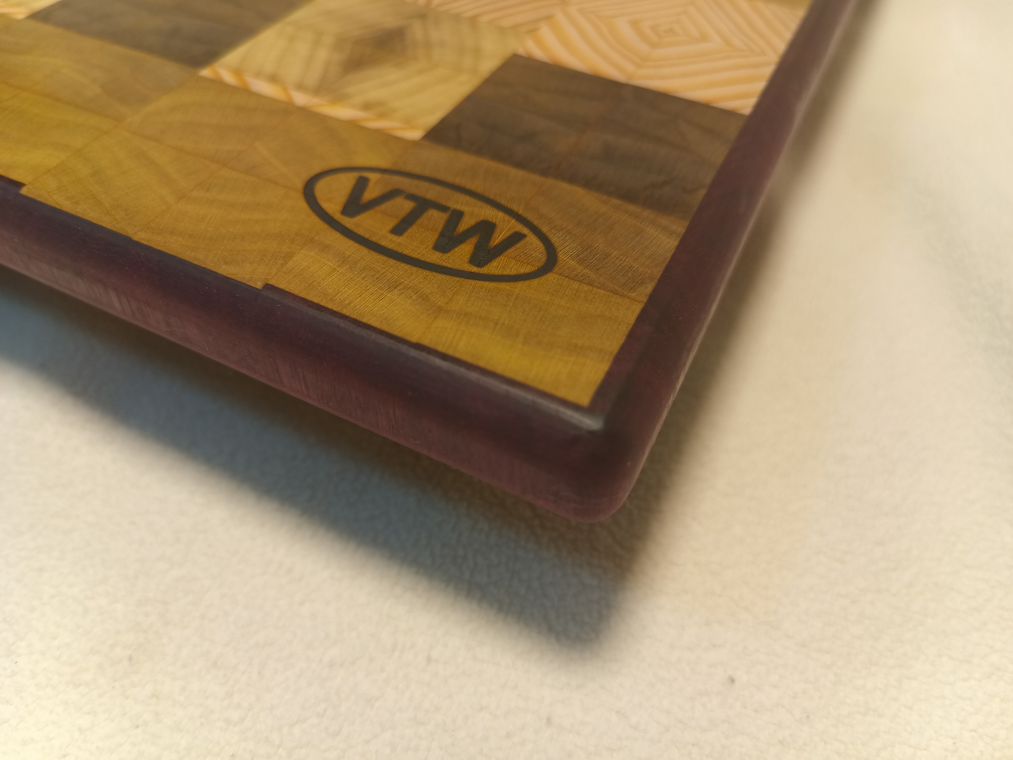 vtw versatile trees woodwork corner view of a thin, large size end grain cutting board made with purple heart walnut, Hemlock, and Poplar. Perfect for a home or professional chef, this board provides a usable work area without raising the work surface very far above the counter top and softer woods are easier on expensive knives