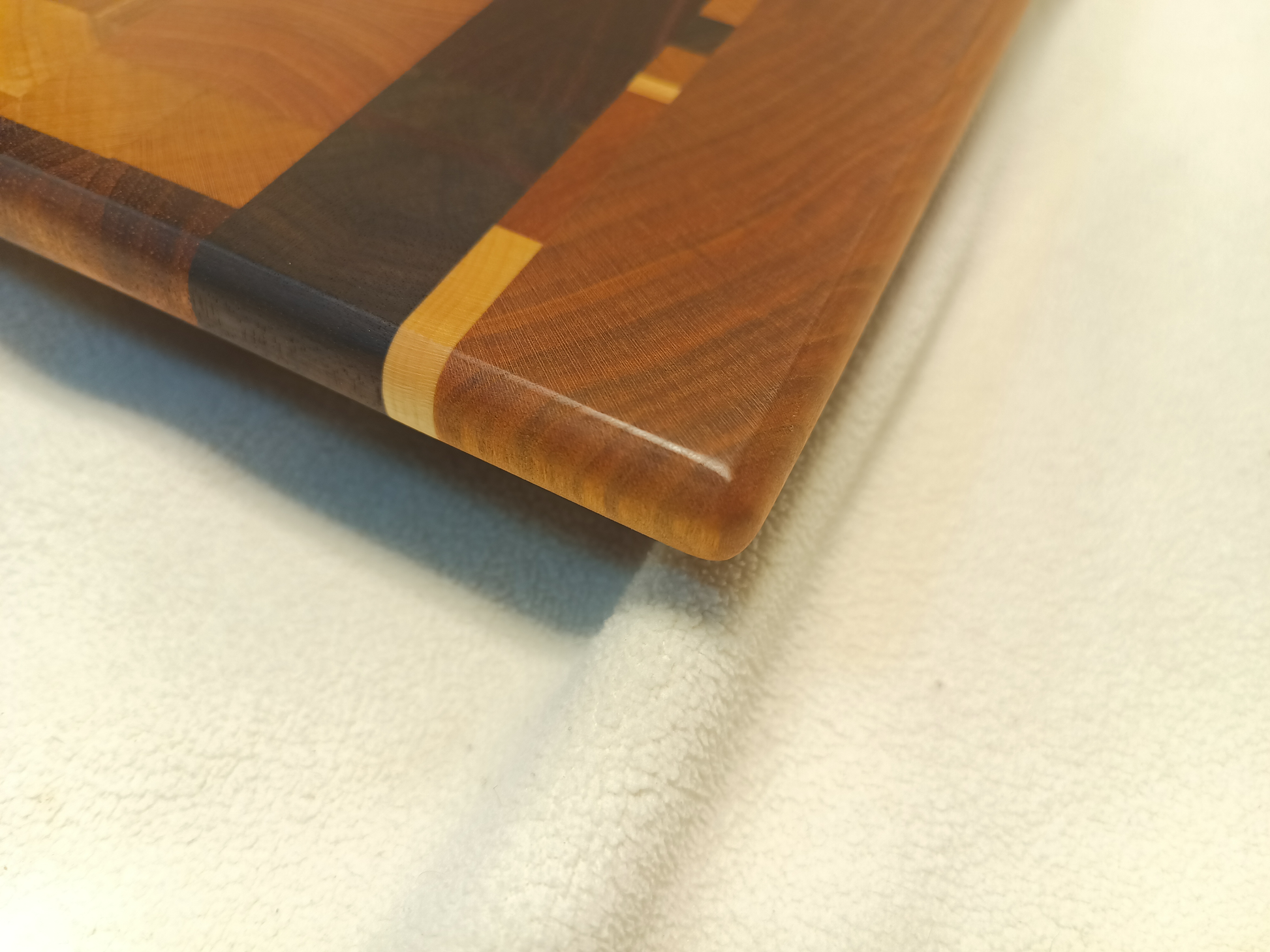 vtw versatile trees woodwork corner view of a thin, large size end grain cutting board made with walnut, hickory, maple, mahogany, and cherry. Perfect for a home or professional chef, this board provides a usable work area without raising the work surface very far above the counter top